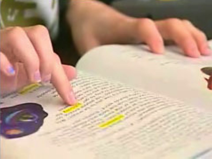 Student's finger pointing to what he/she is reading in a book.